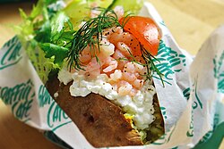 A baked potato with shrimp, cottage cheese, dill, tomato and lettuce from a Swedish café