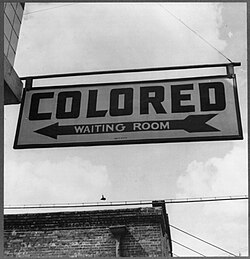 A so-called "Colored" waiting room sign in 1943 at a bus terminal in Rome, Georgia, where Jim Crow laws created "de jure" legally required segregation