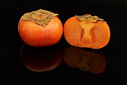 Oriental persimmon fruit, whole and halved, of the firm cultivar 'fuyu'