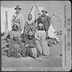 L to R, standing: US Indian agent, Winema (Tobey) Riddle, a Modoc; and her husband Frank Riddle, with four Modoc women sitting in the front two rows. Photographed by Eadweard Muybridge, 1873.
