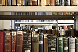 Books on library shelves and call numbers visible on the spines