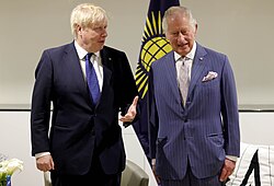 Charles standing next to Johnson with the flag of the Commonwealth of Nations behind them