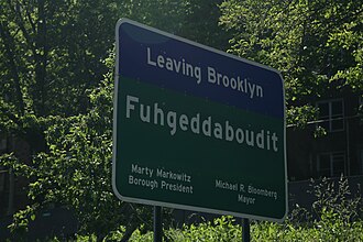 A sign on the periphery of Brooklyn in 2008, that reads "Fuhgeddaboudit" (a pronunciation spelling of "forget about it"), illustrating the "Brooklyn accent"'s non-rhoticity and t-voicing