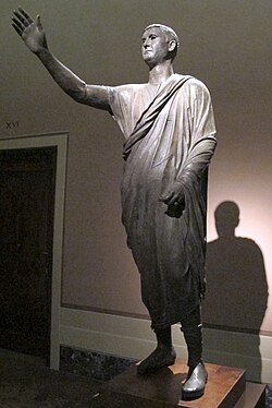 The Orator, c. 100 BC, from the National Archaeological Museum of Florence, Italy, an Etrusco-Roman bronze statue depicting Aule Metele (Latin: Aulus Metellus), an Etruscan man wearing a Roman toga while engaged in rhetoric; the statue features an inscription in the Etruscan language