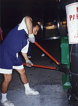An unidentified City of Chicago Streets and Sanitation worker illegally cuts the cable on a Chicago Jewish Star news box at the southwest corner of Michigan and Adams on the night of June 22, 1994. The City of Chicago had previously denied that any City worker had been authorized to move Jewish Star newsboxes.