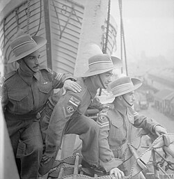 Three Assyrian Iraq Levies, who volunteered in 1946 for service as ground crew with the Royal Air Force, look over the side of the ORBITA as it pulls into the docks at Liverpool. Left to right, they are: Sergeant Macko Shmos, Lance Corporal Adoniyo Odisho and Corporal Yoseph Odisho.