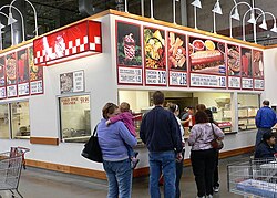 Food concession stand at the Costco warehouse in Overland Park, Kansas with the Costco hot dog displayed in the most prominent position on the menu