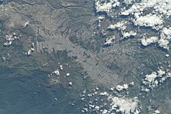 View of Quito from the International Space Station (north is at the left of the image). Quito sits on the eastern slopes of the Pichincha Volcano, whose crater is visible.