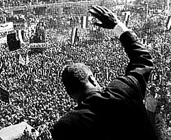 The back of a man waving to the throng below