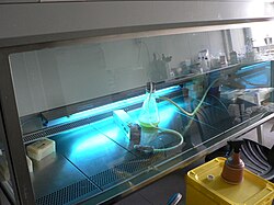 A low-pressure mercury vapor discharge tube floods the inside of a hood with shortwave UV light when not in use, sterilizing microbiological contaminants from irradiated surfaces.