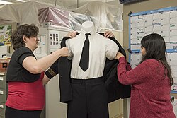 A curator and exhibit designer dressing a mannequin for an exhibit