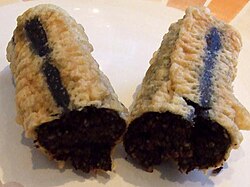 A single battered deep-fried chip shop black pudding (approx. 20 cm long), sliced open