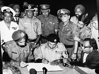Pakistan's Lt. Gen. A. A. K. Niazi signing the Instrument of Surrender under the gaze of Lt. Gen. J. S. Aurora, the head of the Indian Army's Eastern Command, on 16 December 1971, in Dhaka.