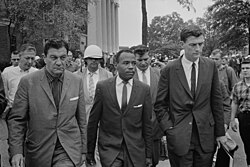 James Meredith walking to class accompanied by a U.S. Marshal and a Justice Department official.