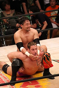 Tajiri performs a camel clutch submission hold on René Duprée.