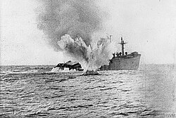 A U-boat shells a merchant ship which has remained afloat after being torpedoed.