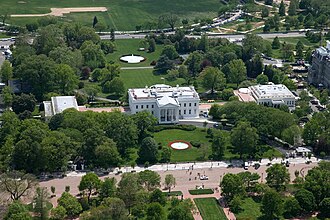 An aerial view of the White House complex, including Pennsylvania Avenue (closed to traffic) in the foreground, the Executive Residence and North Portico (center), the East Wing (left), and the West Wing and the Oval Office at its southeast corner in April 2007