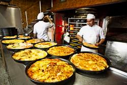 Traditional Argentine-style pizzas de molde being prepared at a pizzeria in Buenos Aires