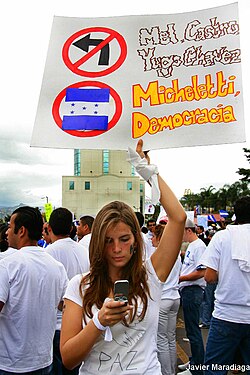 Honduran demonstrator holding a banner with a "don't turn left" sign, 2009