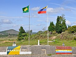 A white marker, with Brazilian and Venezuelan flags on either side