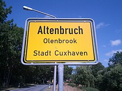 City limit sign in Lower Saxony showing that Low German is closer to English for Altenbruch (meaning 'old bog/swamp'), an incorporated village of Cuxhaven. The name in Low German is Olenbrook.