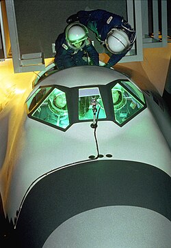 Langley volunteers, wearing flight suits and helmets, were put through a series of tests with the craft placed both vertically and horizontally to simulate launch and landing attitudes.