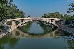 A graceful stone bridge spanning a river, with trees in the background