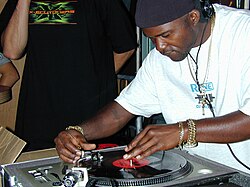 In the early 1970s in the South Bronx Grand Wizzard Theodore invented the "DJ scratch" technique, here he is doing his famous "needle drop" at the Experience Music Project in Seattle 2002