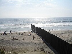 A border wall on a beach separating the United States and Mexico