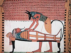 Anubis, the god associated with mummification and burial rituals, attending to a mummy