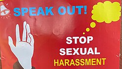 A white hand is raised against a red background, with a megaphone next to the words "SPEAK OUT!" and a yellow thought bubble coming from "STOP SEXUAL HARASSMENT"