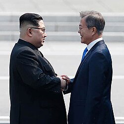 Kim and Moon shaking hands over the demarcation line on 27 April 2018