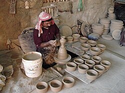 An artisan making pottery using the traditional mud and water mixture on a revolving wheel