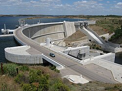 Alqueva dam with a road across its crest holds back a reservoir in a rural landscape.