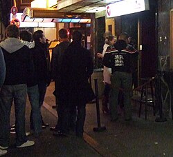 A bouncer checks patrons' IDs at the entrance to a nightclub