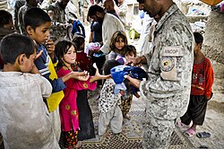 Foreign donated clothing being handed out by an Afghan civil officer to children at a refugee camp, 2011