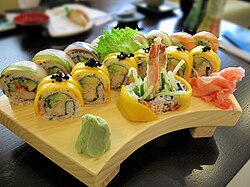 Rainbow roll, uramaki with multiple fillings including shrimp tempura, salmon, avocado, mango, with rice mixed with tobiko