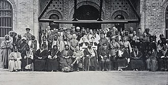 Ibn Saud as a guest of Shaikh Khaz'al in Mohammerah. The image includes Sheikh Khaz'al, Emir of Arabistan, Ibn Saud, Sir Percy Cox, along with Saudi Arabia dignitaries and other British officials