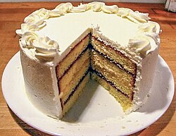 A layer cake made of pound cake, jam, and frosting.