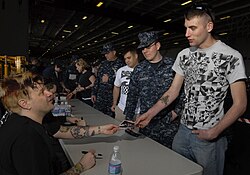 Members of Bowling for Soup signing autographs for sailors aboard the carrier USS John C. Stennis.