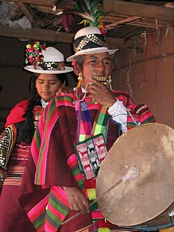 Quechua person playing siku panpipe and caja drum in Sucre