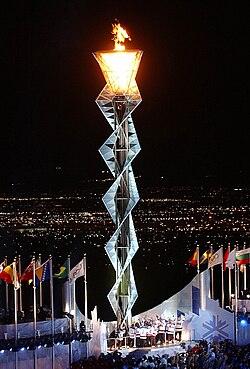 Interwoven steel frame several stories high with the lit flame at the top