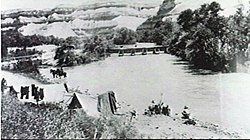 Bivouac on the Jordan River, men washing clothes and exercising horses, with pontoon bridge and the Hills of Moab in the distance