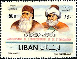 A Lebanese stamp showing two elders, one with a long white bear and wearing a fez, the other with a short white beard wearing a fez and turban and French and Arabic writing marking Lebanese independence day